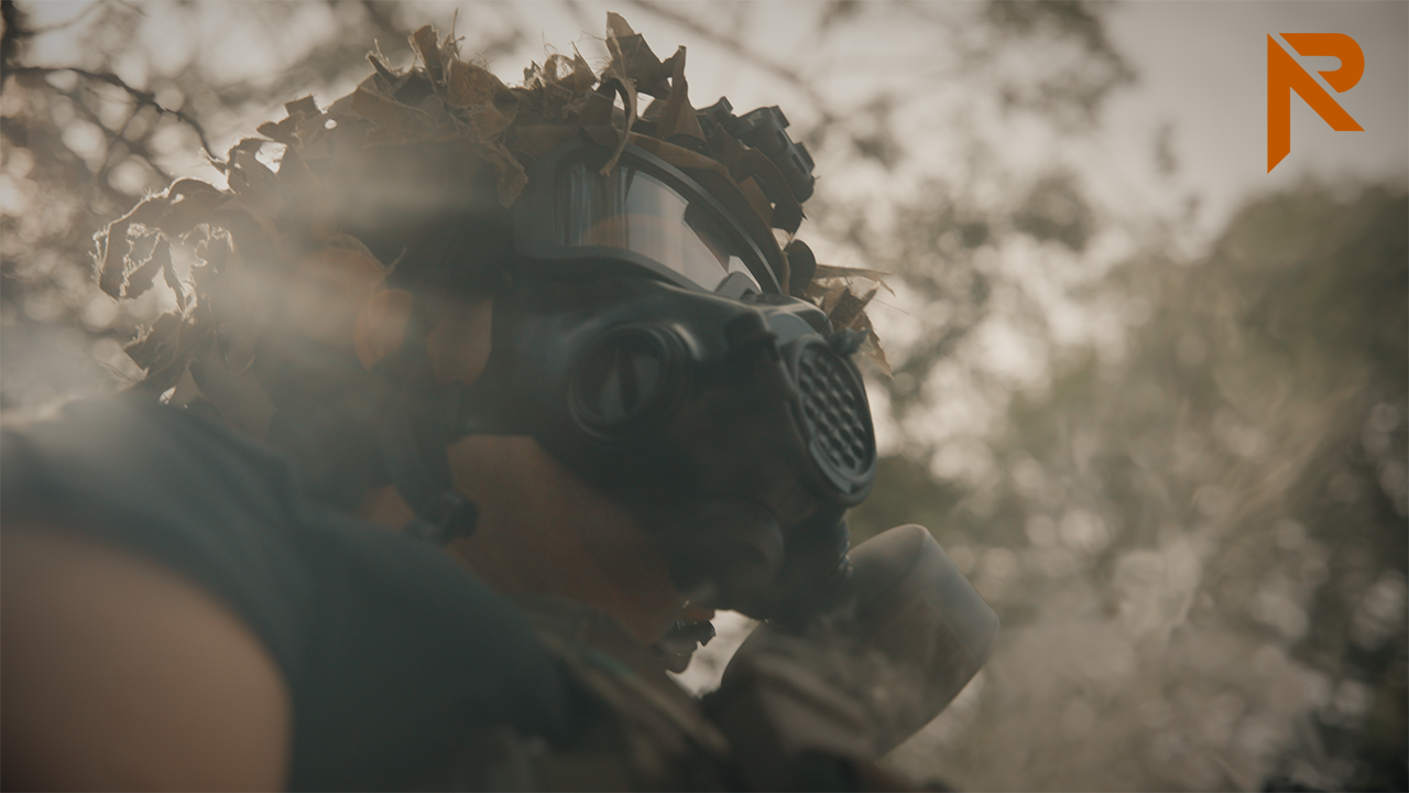 man wearing tactical gas mask in the middle of smoke bomb
